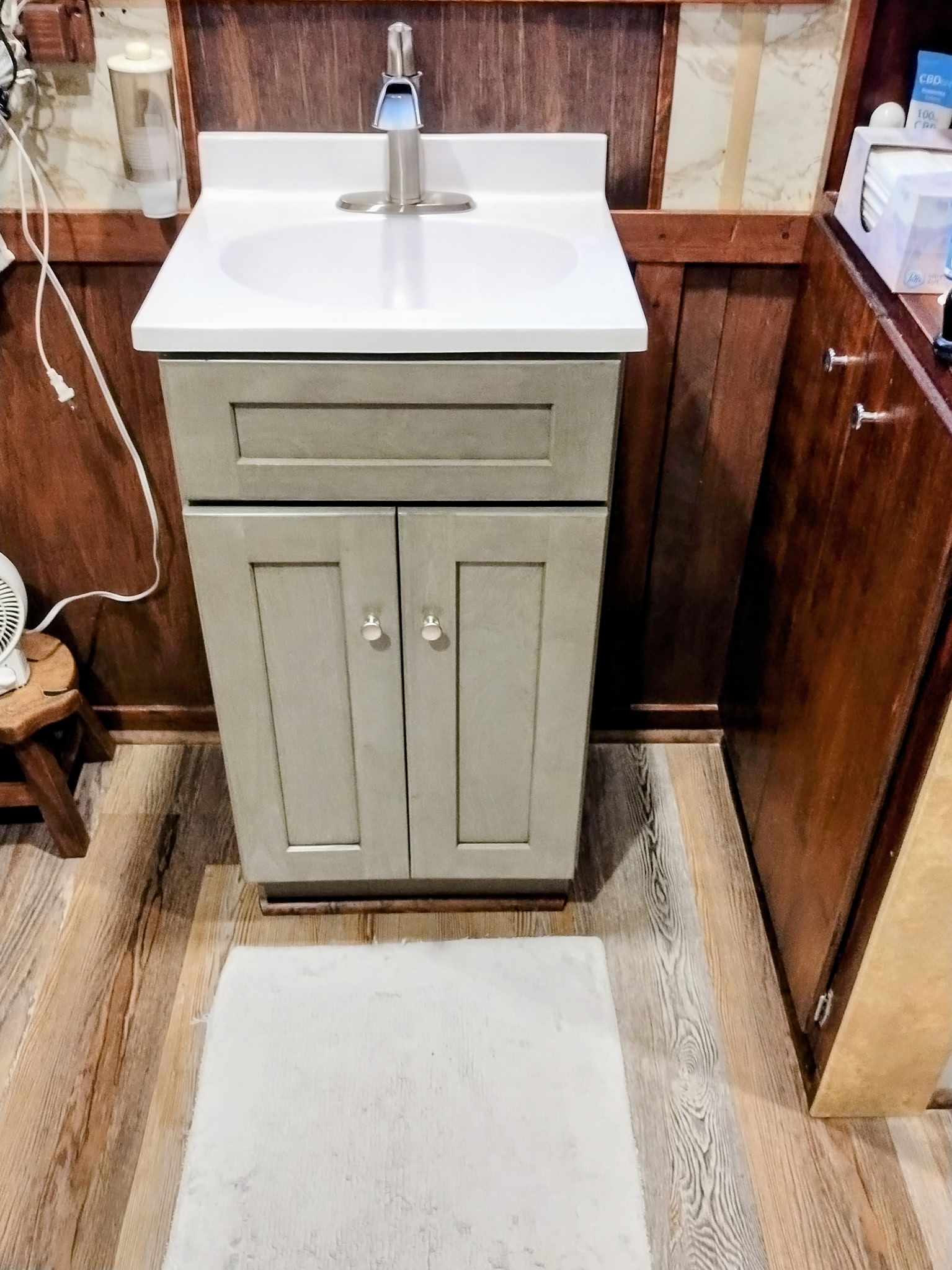 Small bathroom sink with a cabinet below, beige and brown tones.