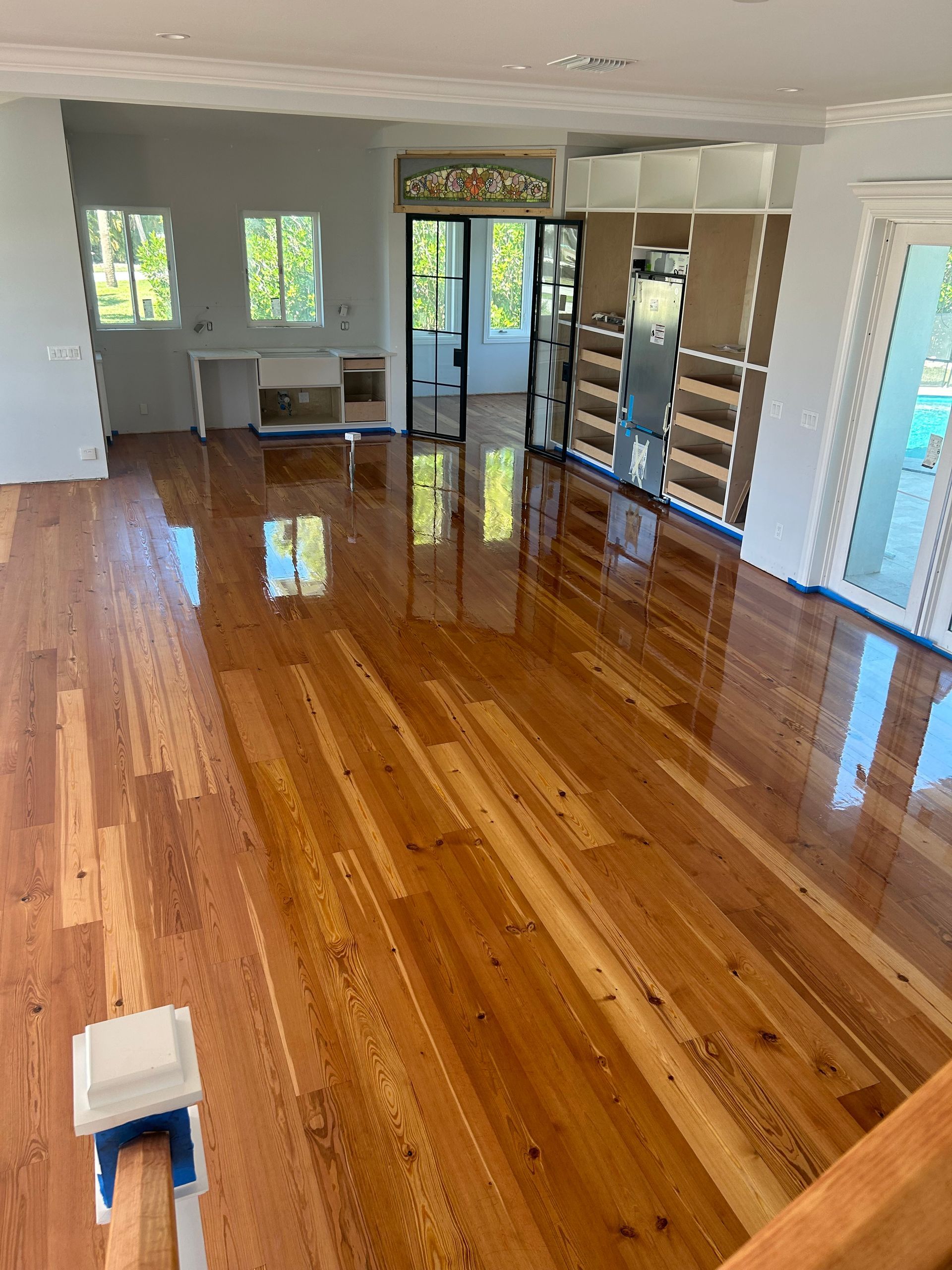 A living room with hardwood floors and a kitchen in the background.