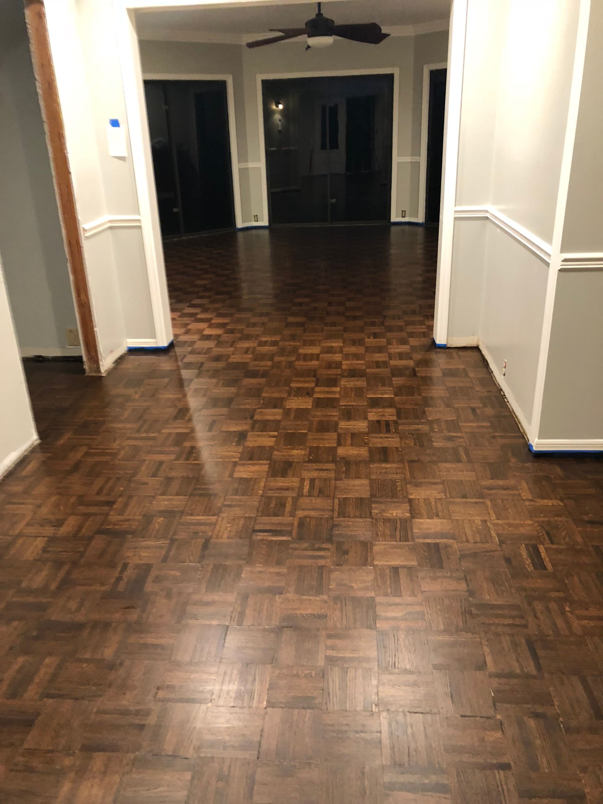 A hallway with a wooden floor and a ceiling fan.