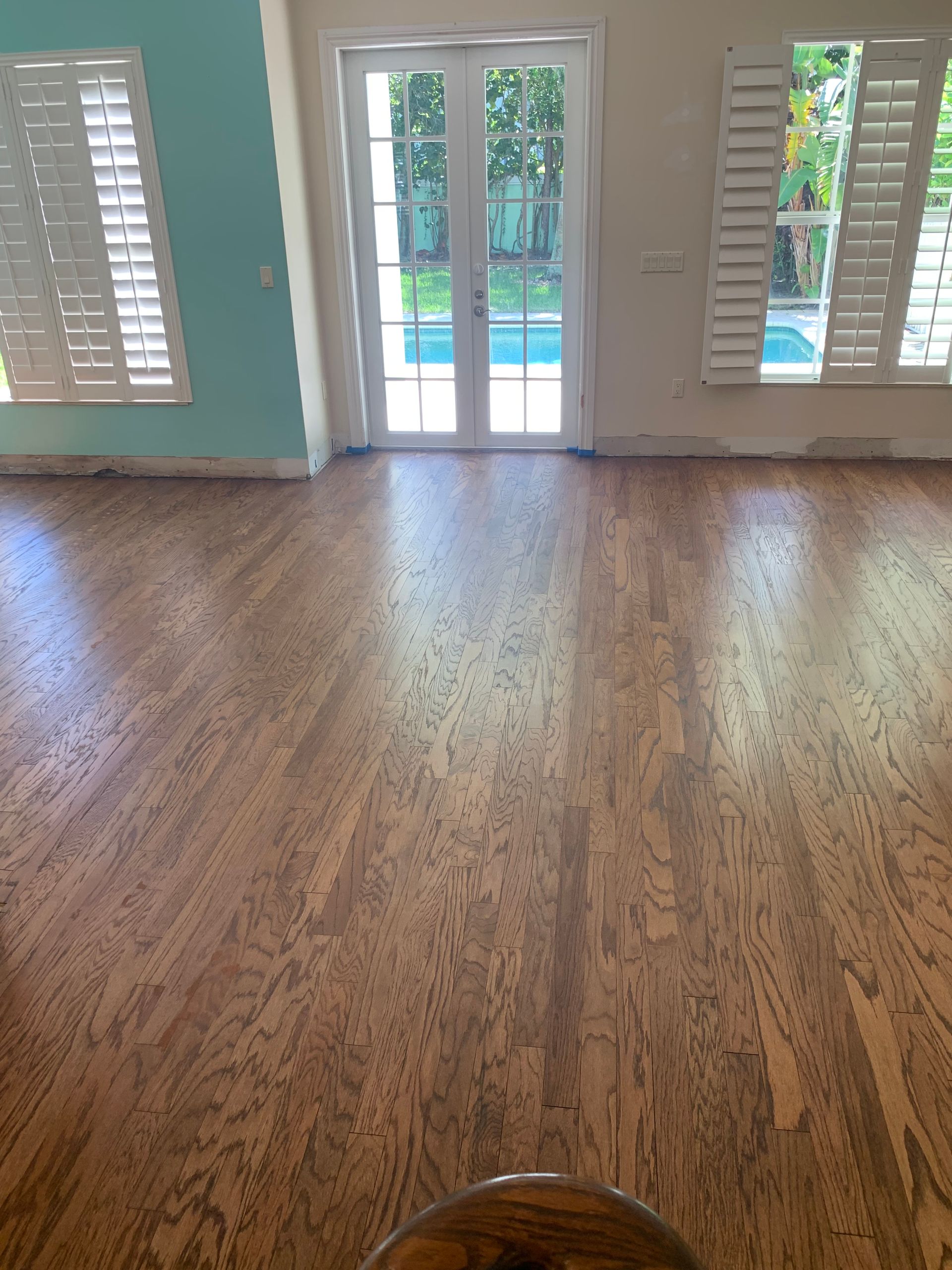 A living room with a wooden floor and shutters on the windows.