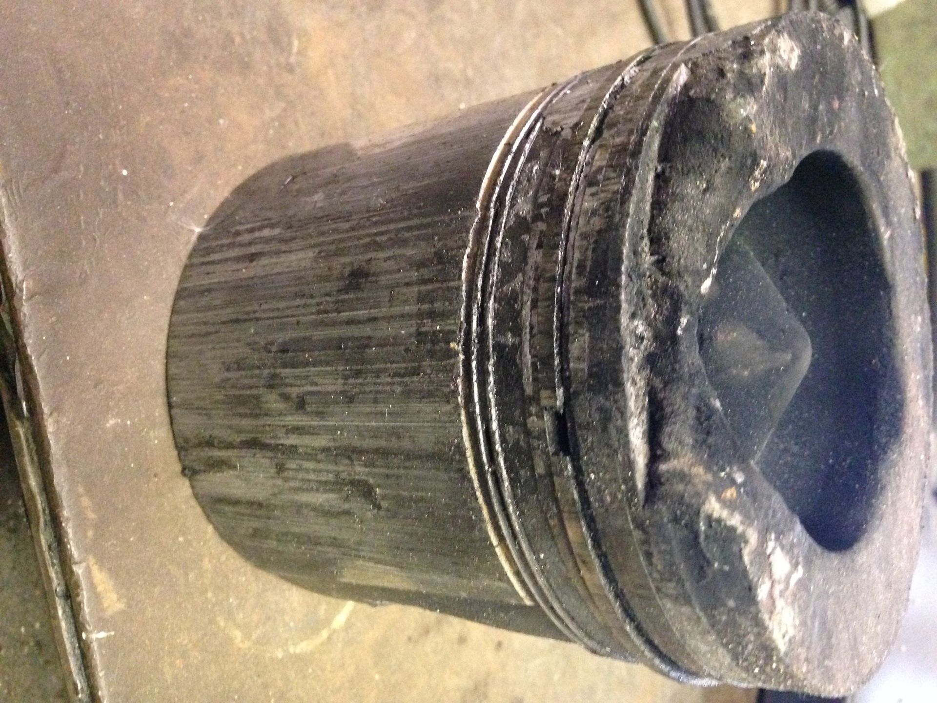Black cylindrical cap or container lying on a dusty surface, viewed from above.
