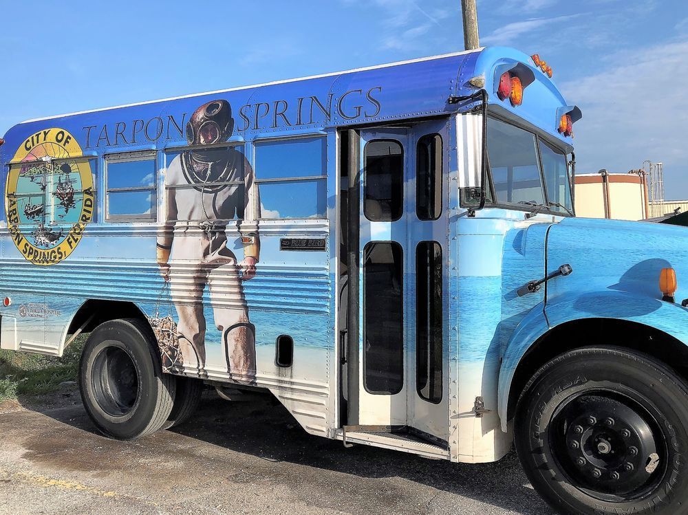 Blue vintage bus with astronaut mural parked outdoors on a sunny day