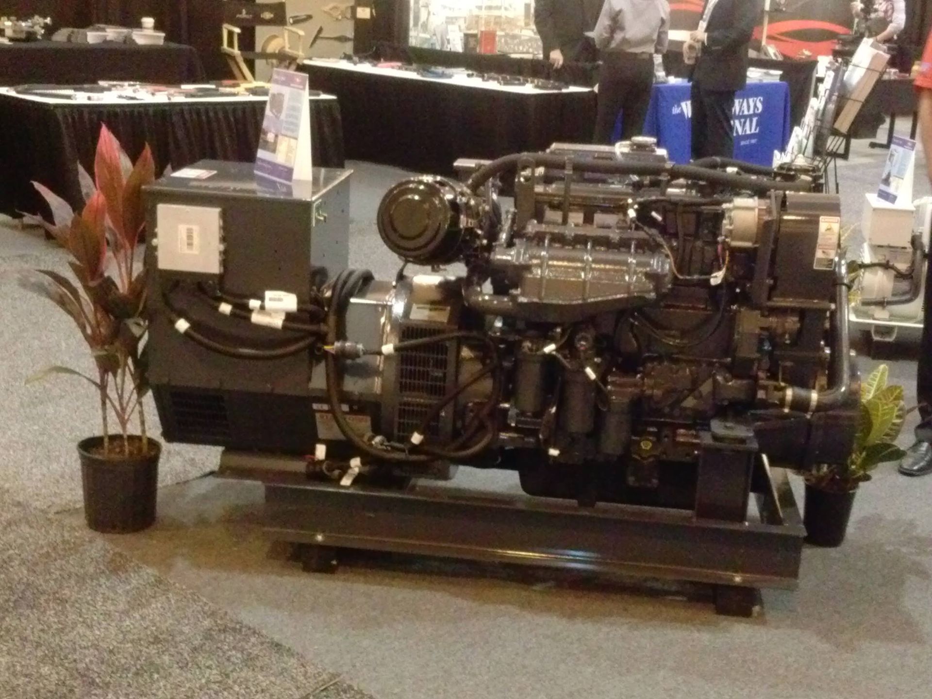 Large industrial engine on a display stand at an indoor trade show booth