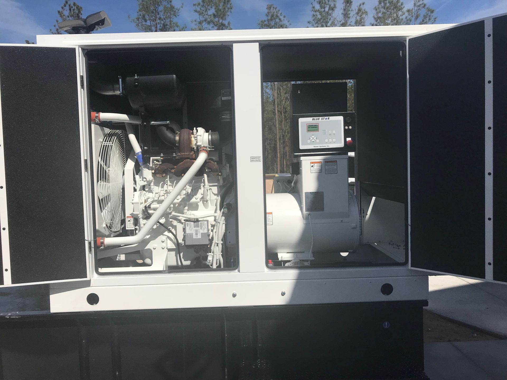 Open generator compartment with engine components and control panel inside a white equipment enclosure