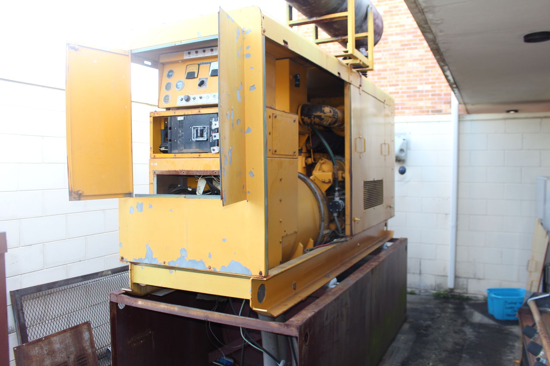 Yellow industrial machine in a tiled utility room, with open panels exposing internal components.