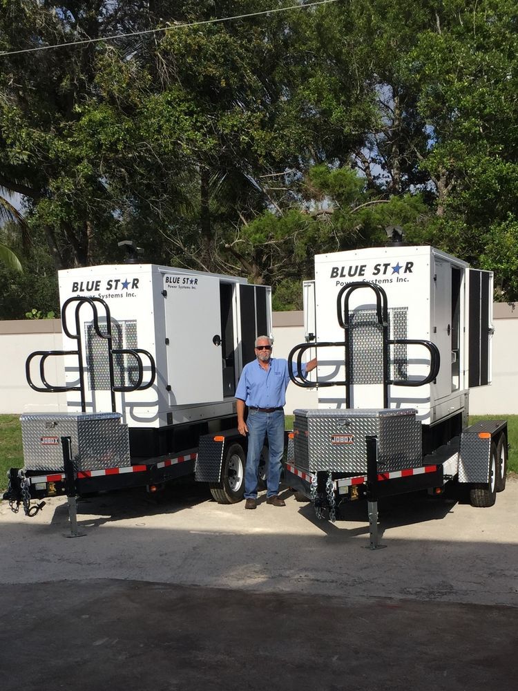 Man standing between two white Blue Star trailers in a sunny outdoor lot