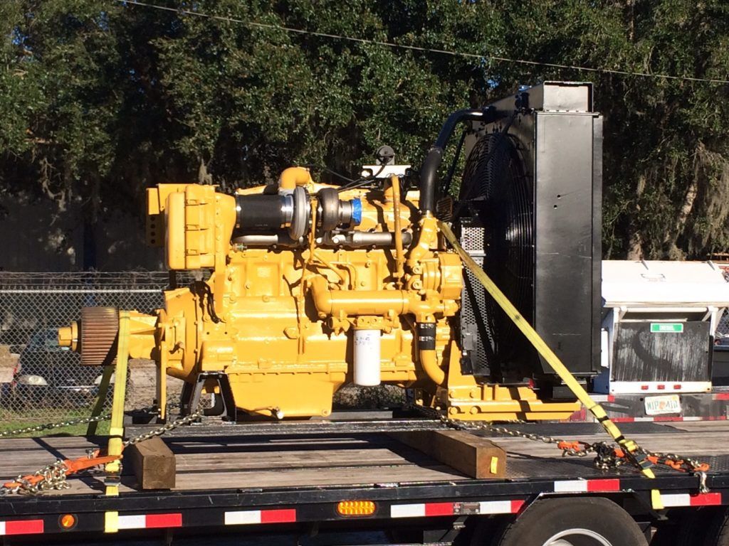 Yellow industrial generator on a trailer with hoses and a black tank outdoors.