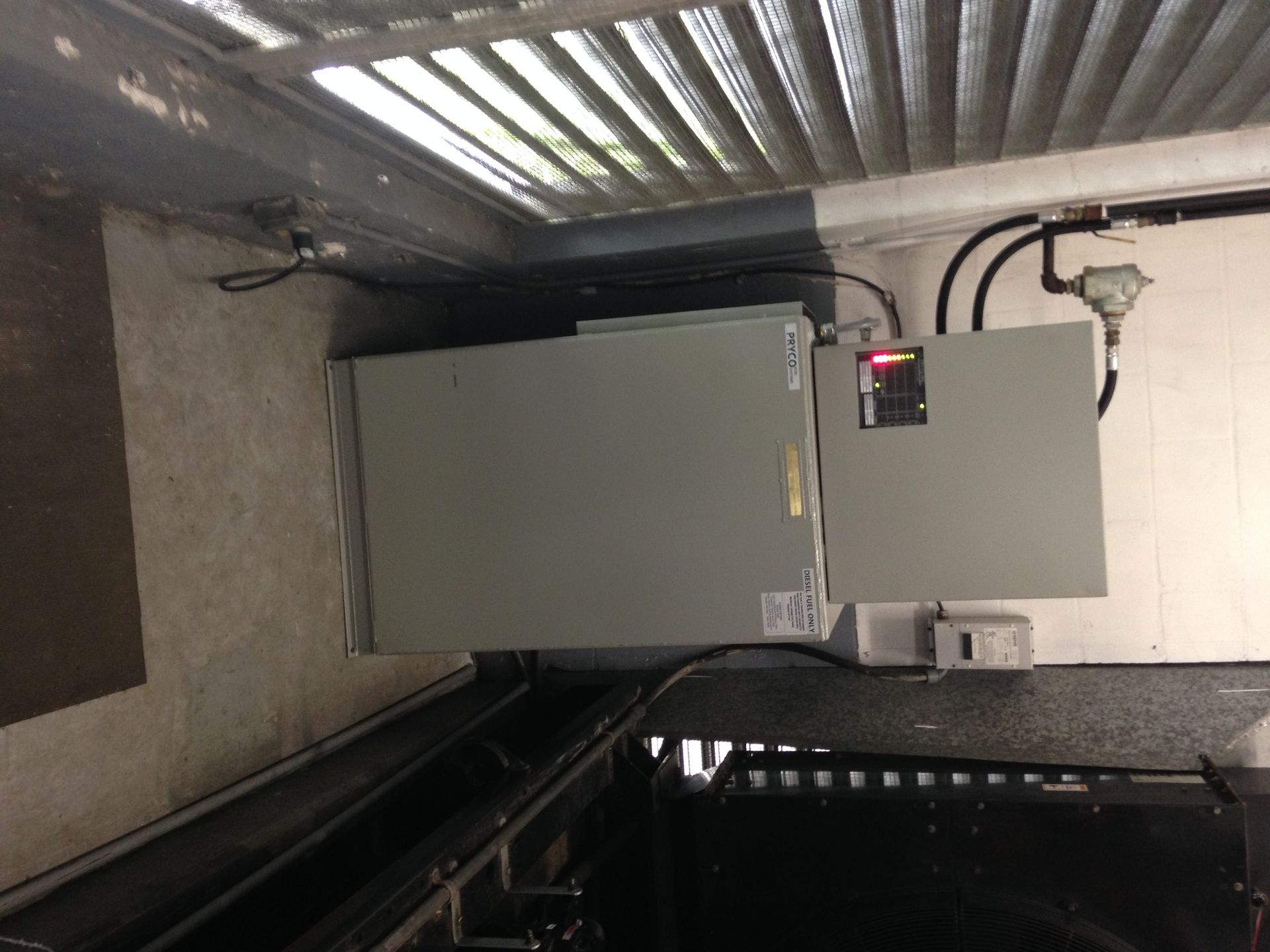 Gray electrical panels and conduit in a utility room beside a corrugated metal wall.