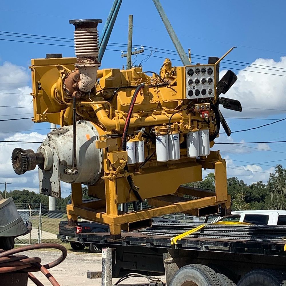 Yellow industrial engine on a trailer under a blue sky, with pipes and components visible.