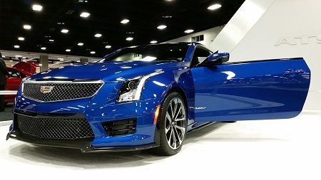 Blue Cadillac sports car on display indoors with the driver’s door open