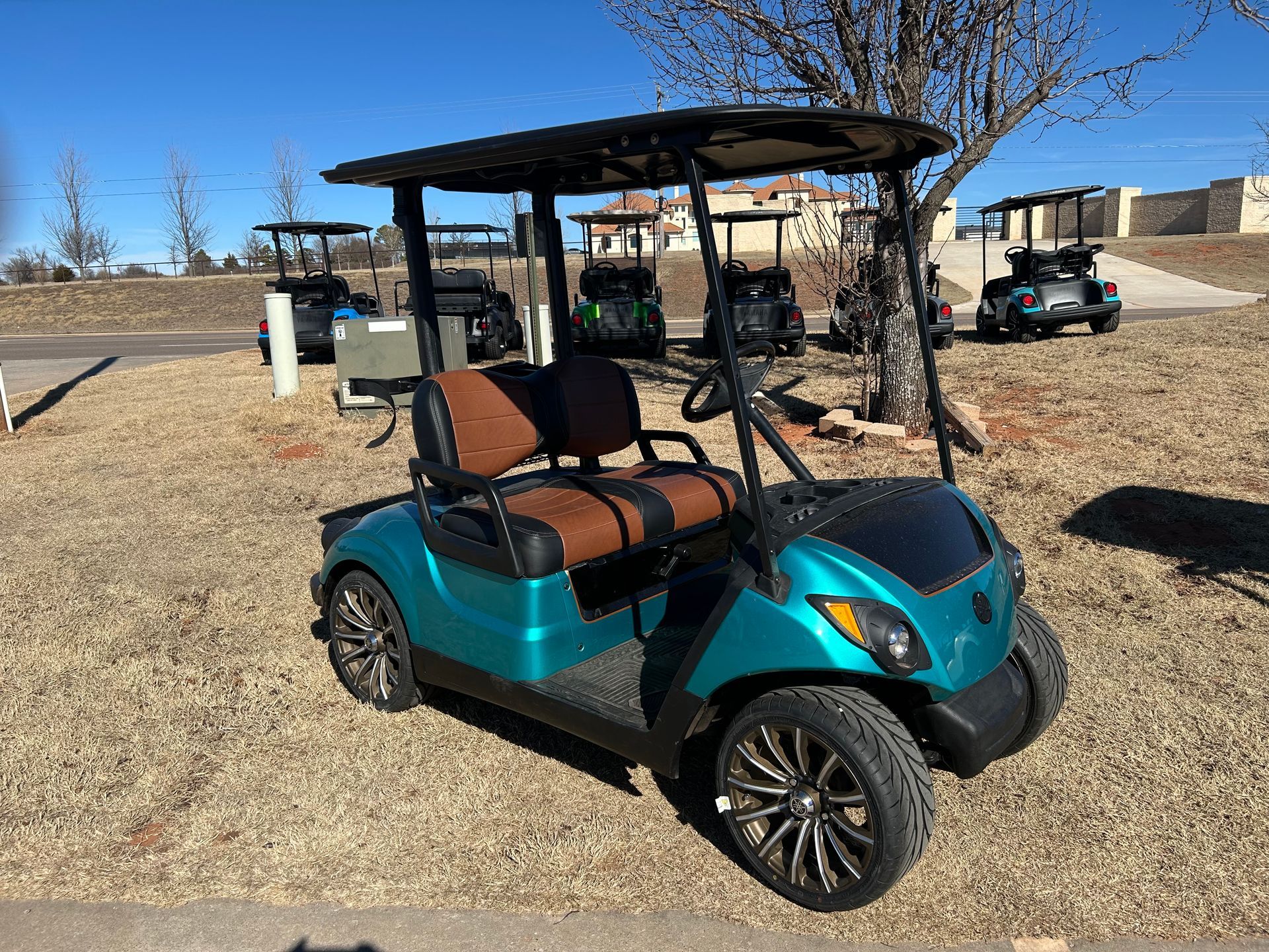 A green golf cart with brown seats is parked in a grassy field
