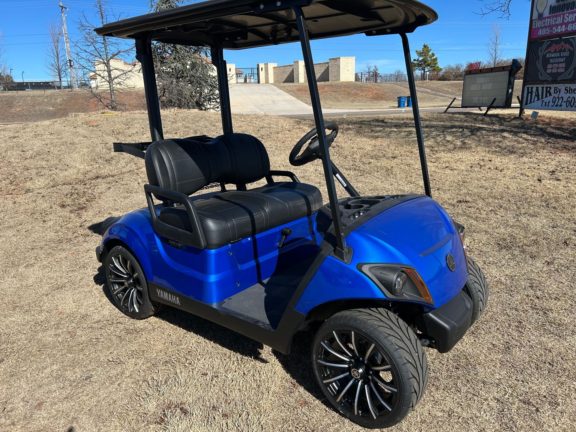A blue golf cart is parked in a dirt field