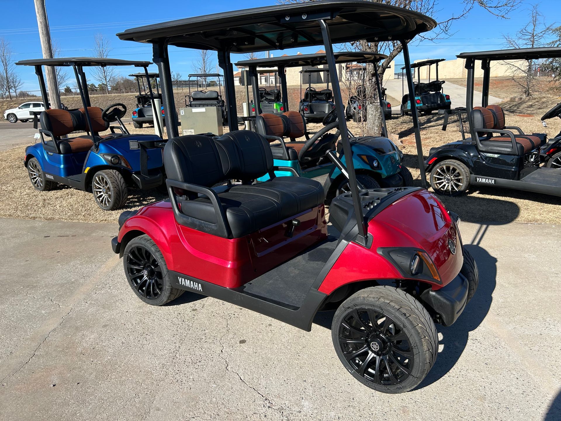 A red golf cart is parked in a parking lot next to other golf carts