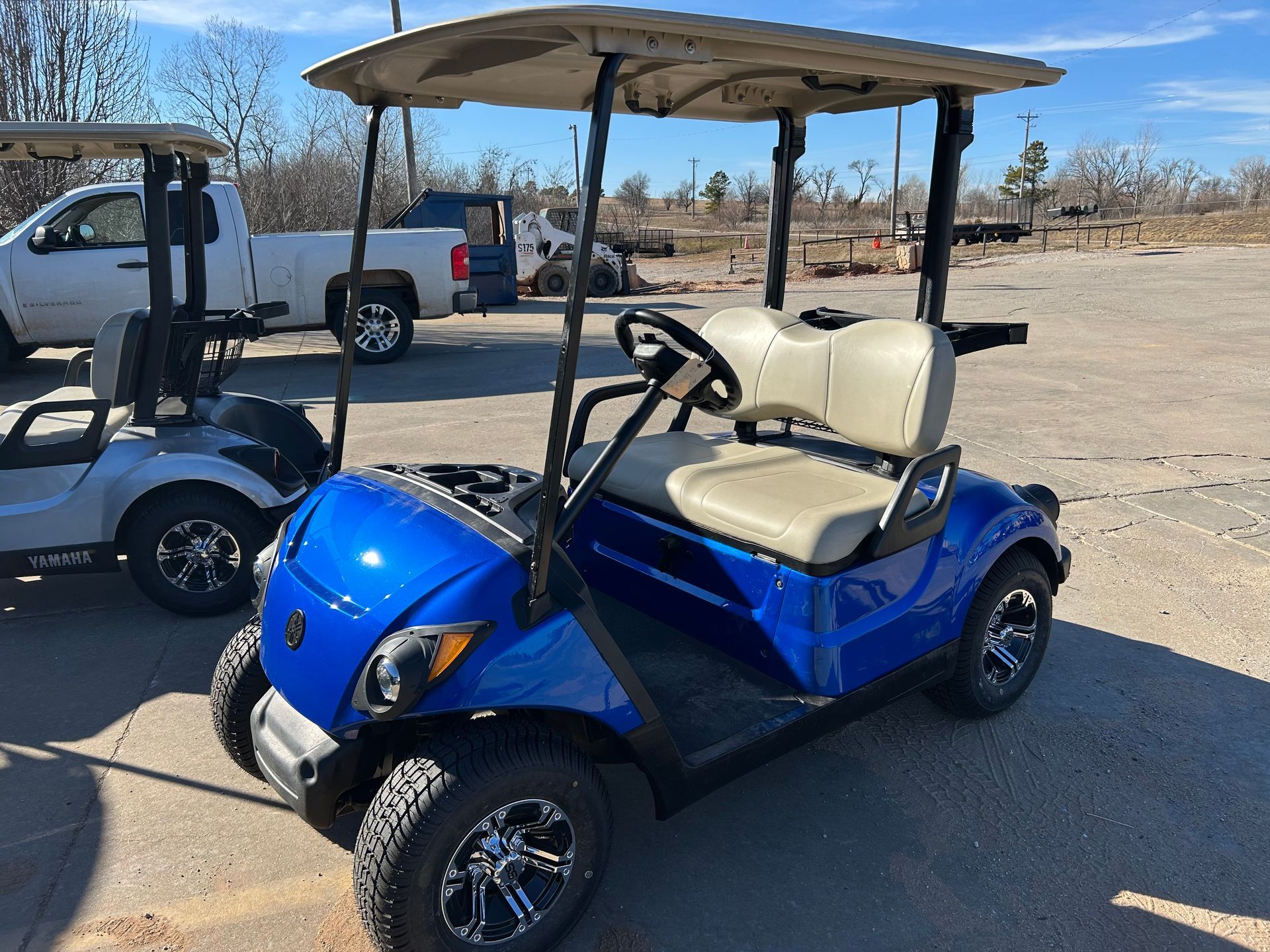 A blue golf cart is parked in a parking lot next to a white truck
