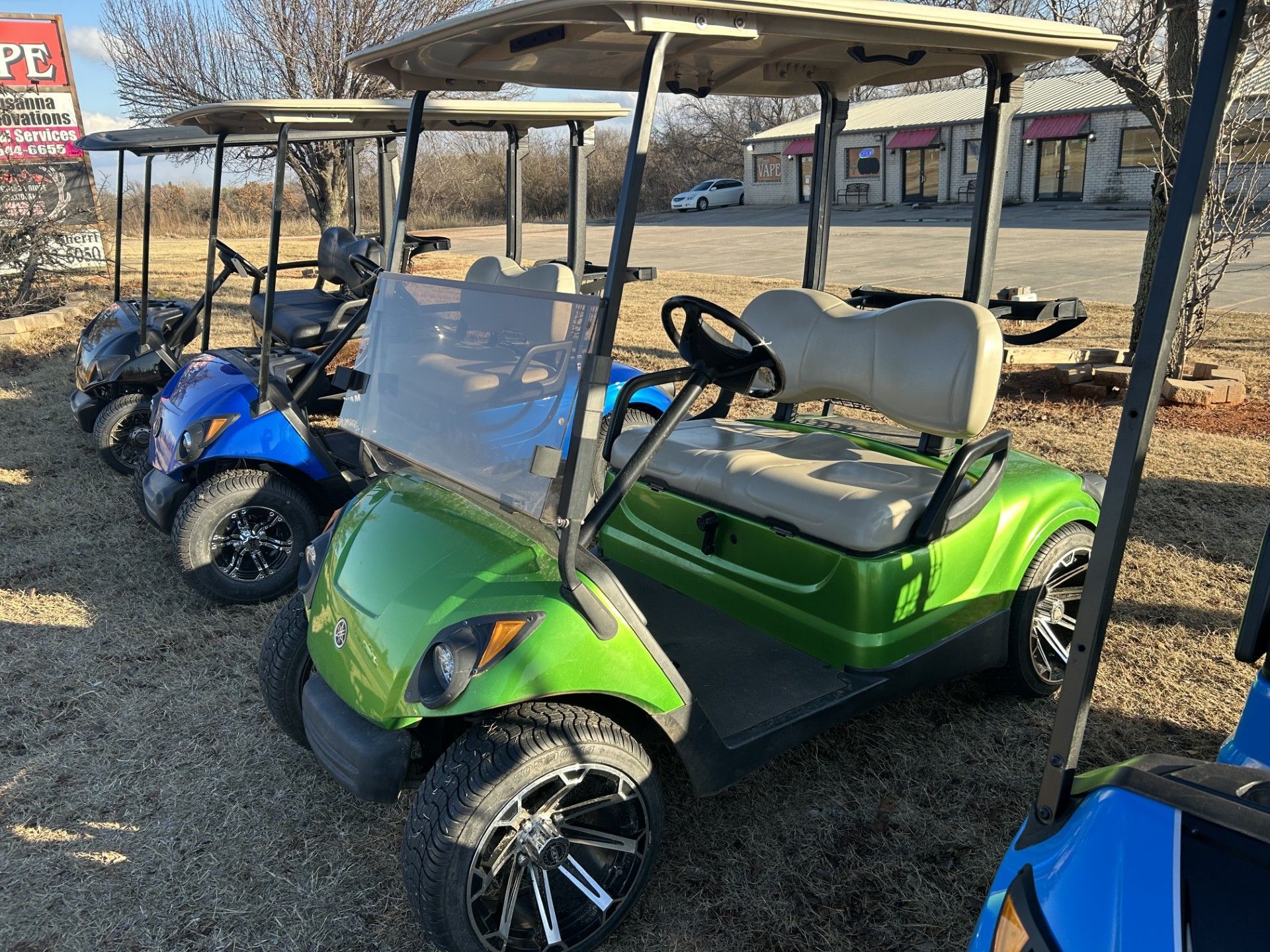A green golf cart is parked in a parking lot.