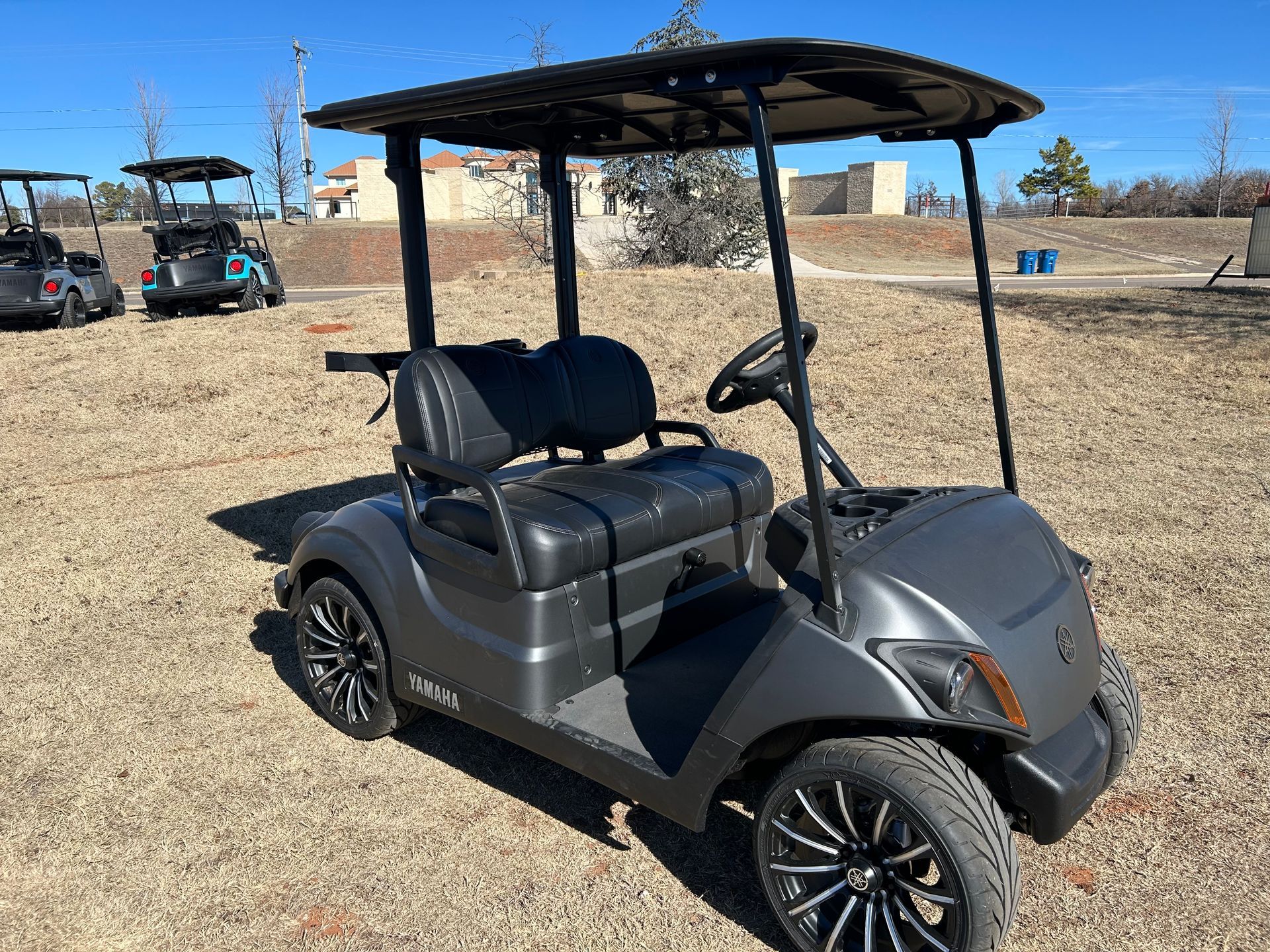 A black golf cart is parked in a dirt field