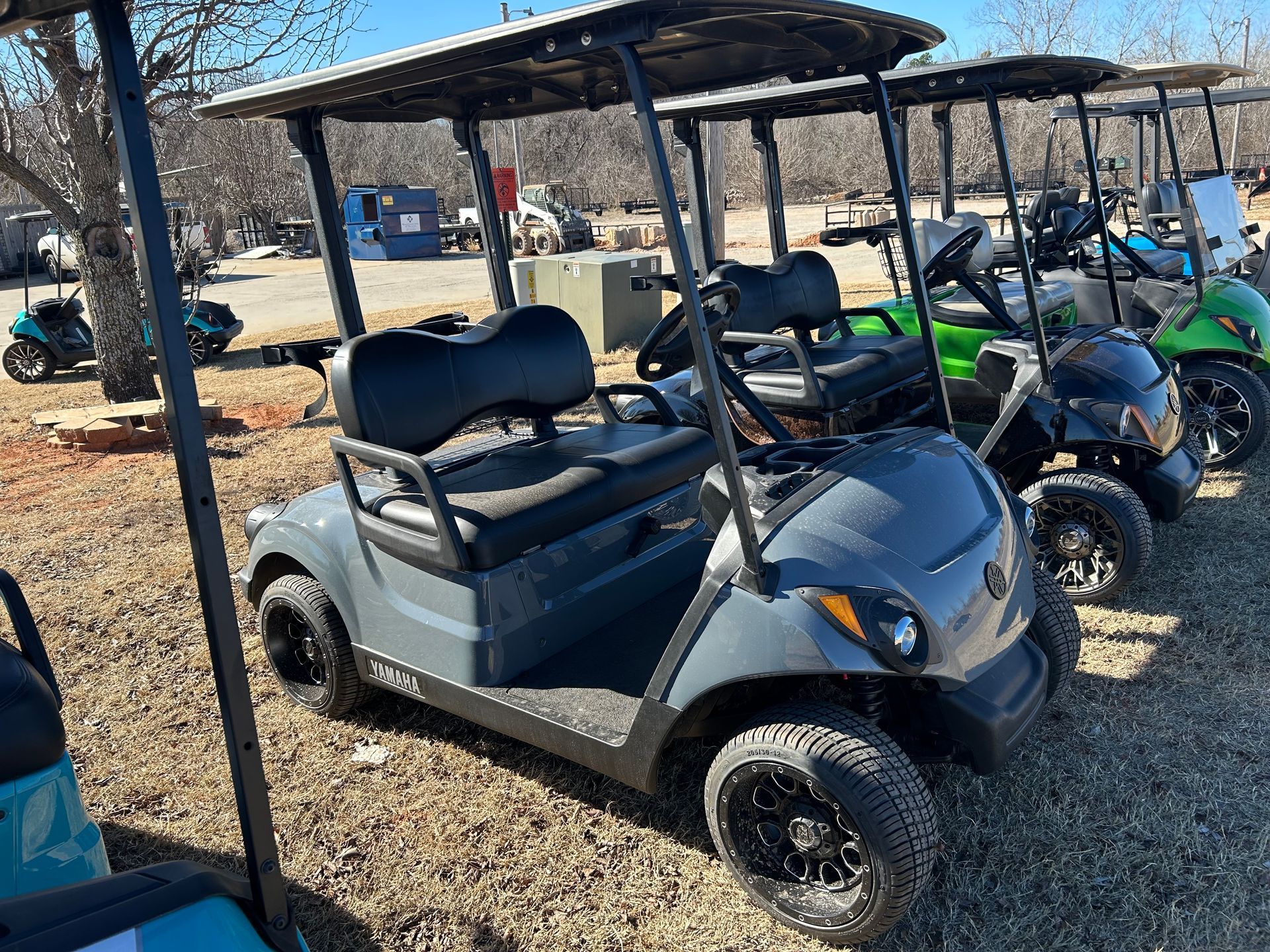 A row of golf carts are parked in a gravel lot