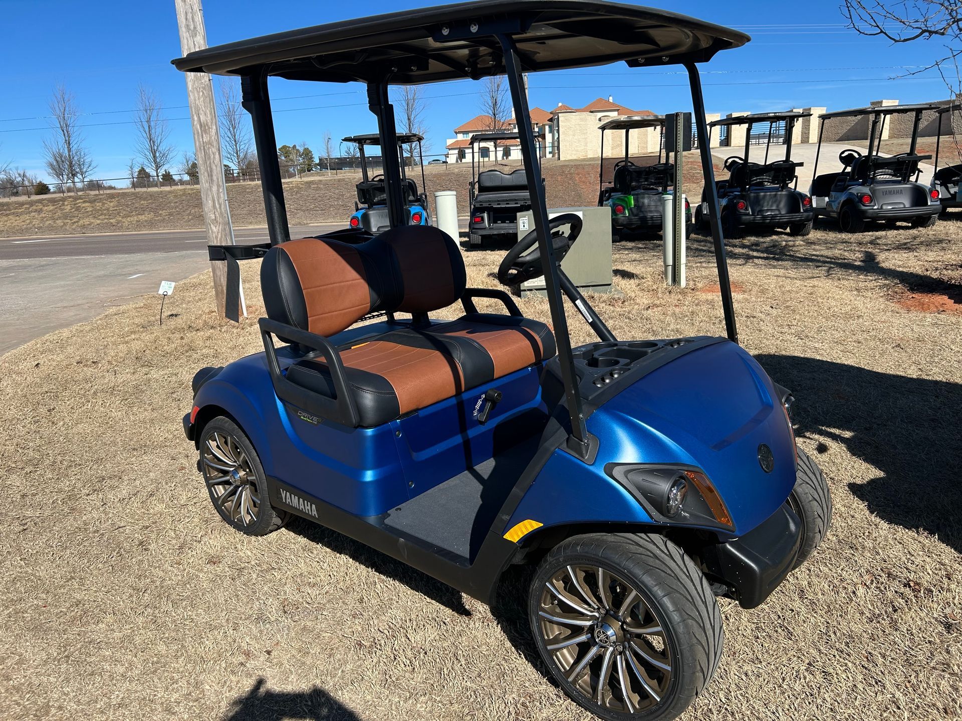 A blue golf cart with brown seats is parked in a gravel lot
