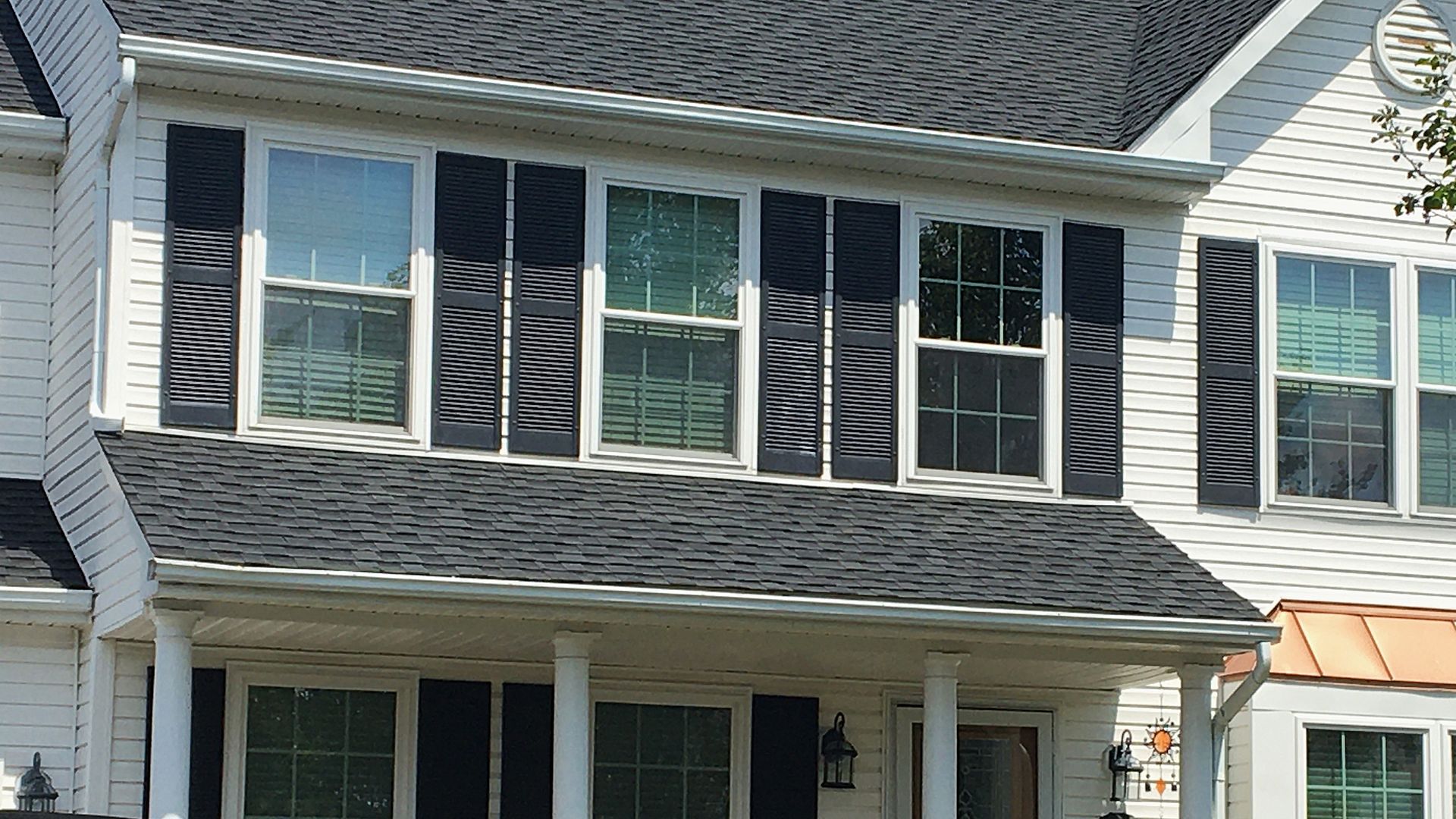 Two-story white house with black shutters on windows; gray roof.