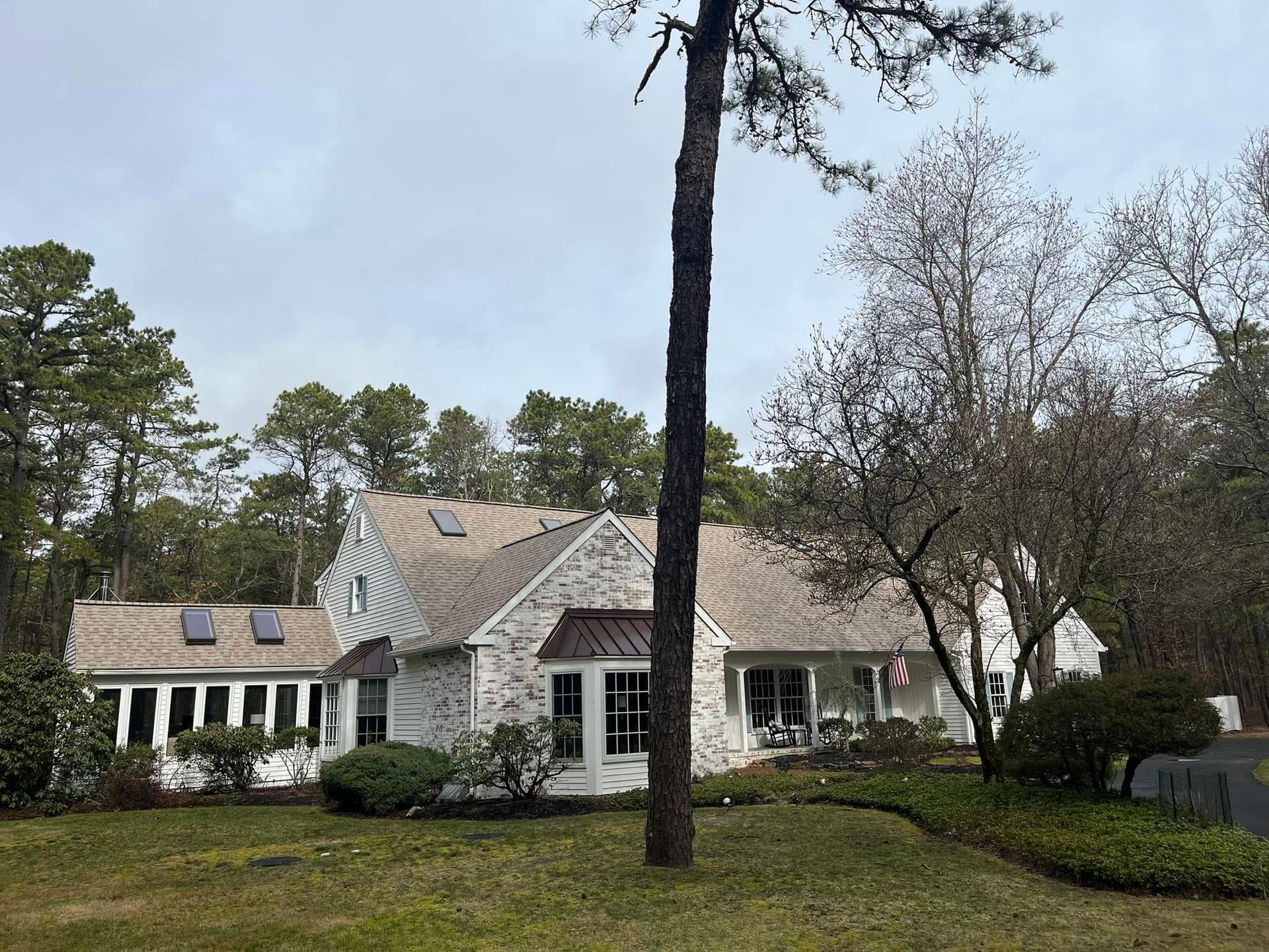 Large stone house with a front porch and tall pine tree in the yard