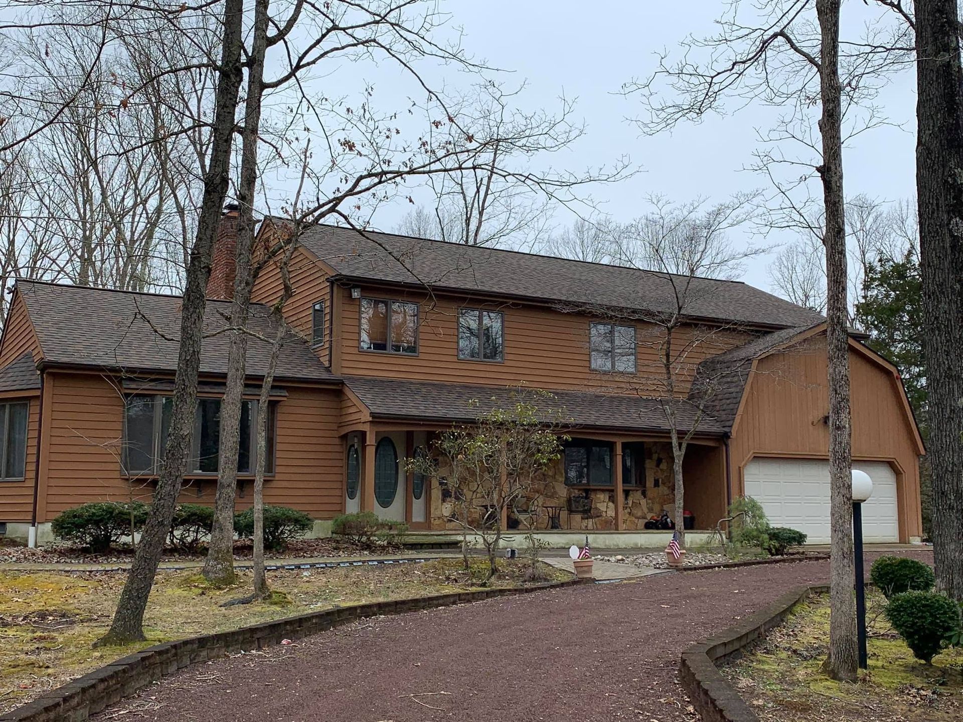 Large two-story brick house with a curved driveway and bare trees in front