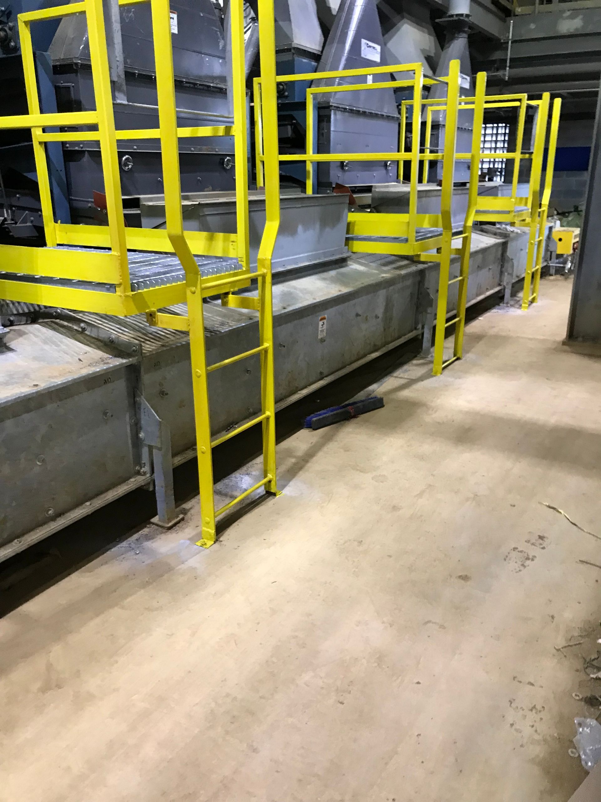 A yellow ladder is attached to a conveyor belt in a factory