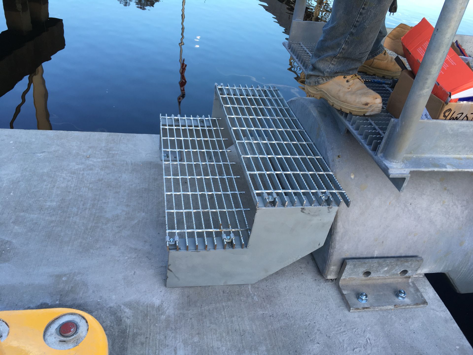 A person standing on a metal staircase next to a body of water