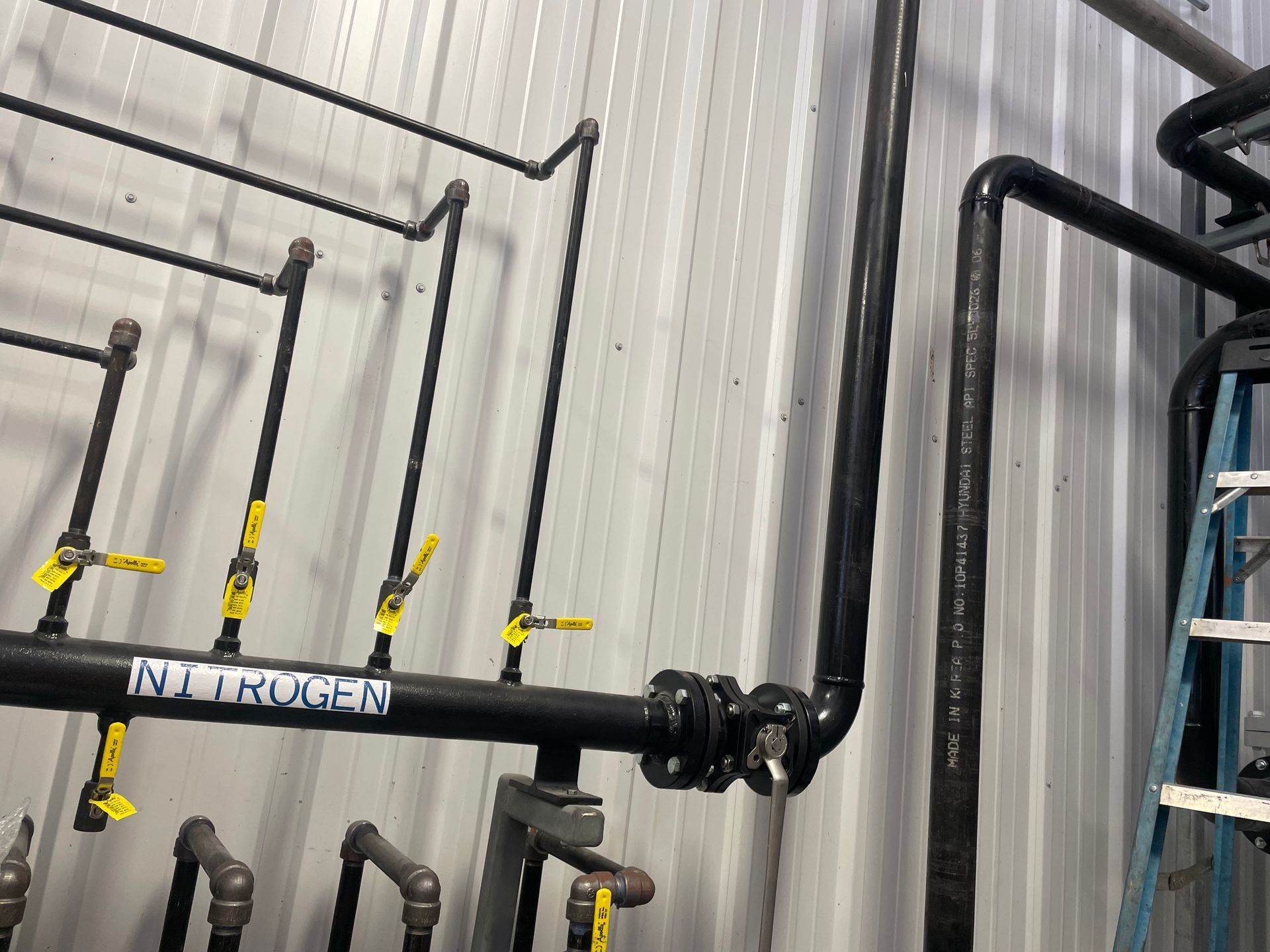 A bunch of pipes are hanging on a wall next to a ladder