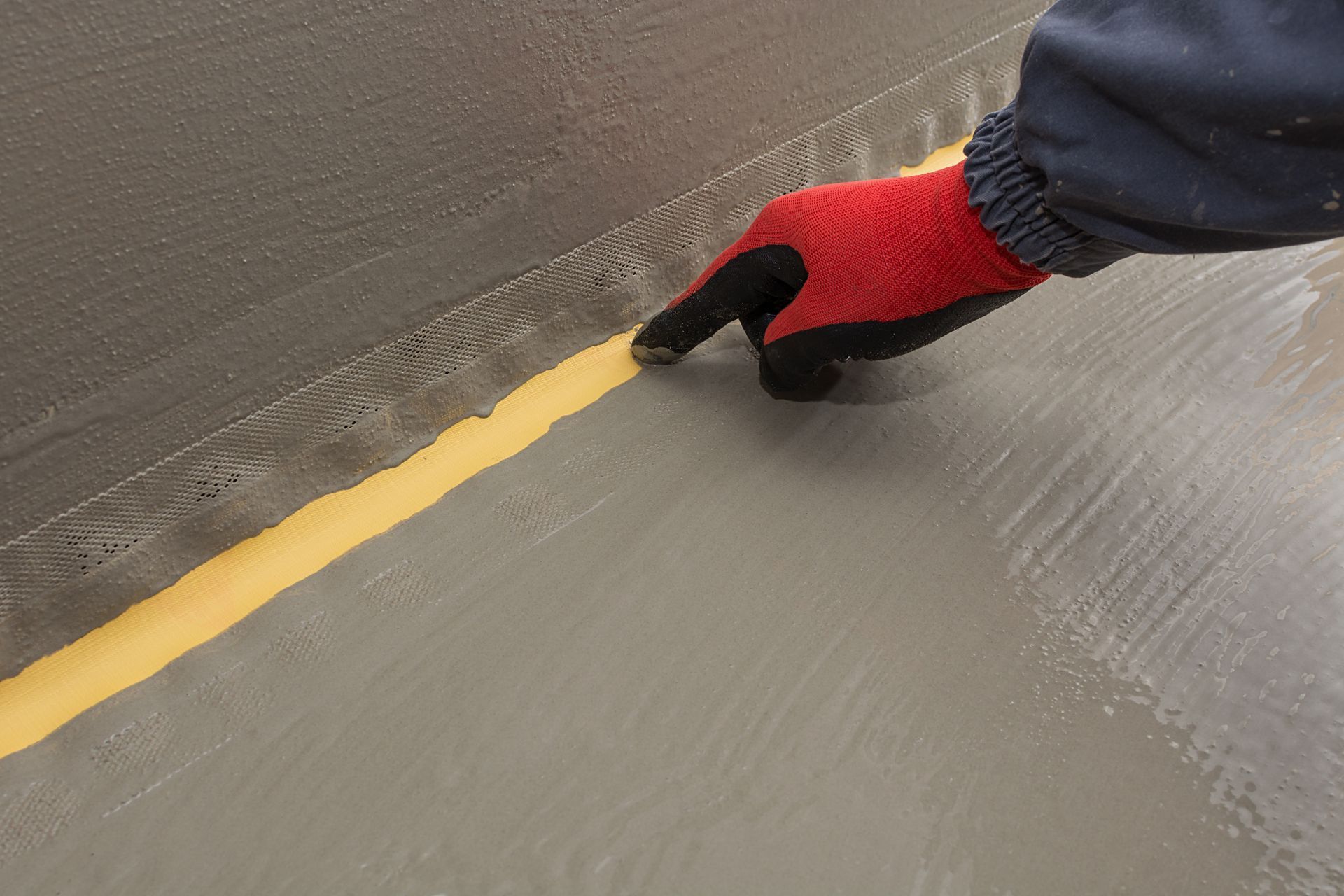 Gloved hand painting a yellow line on a gray pavement surface