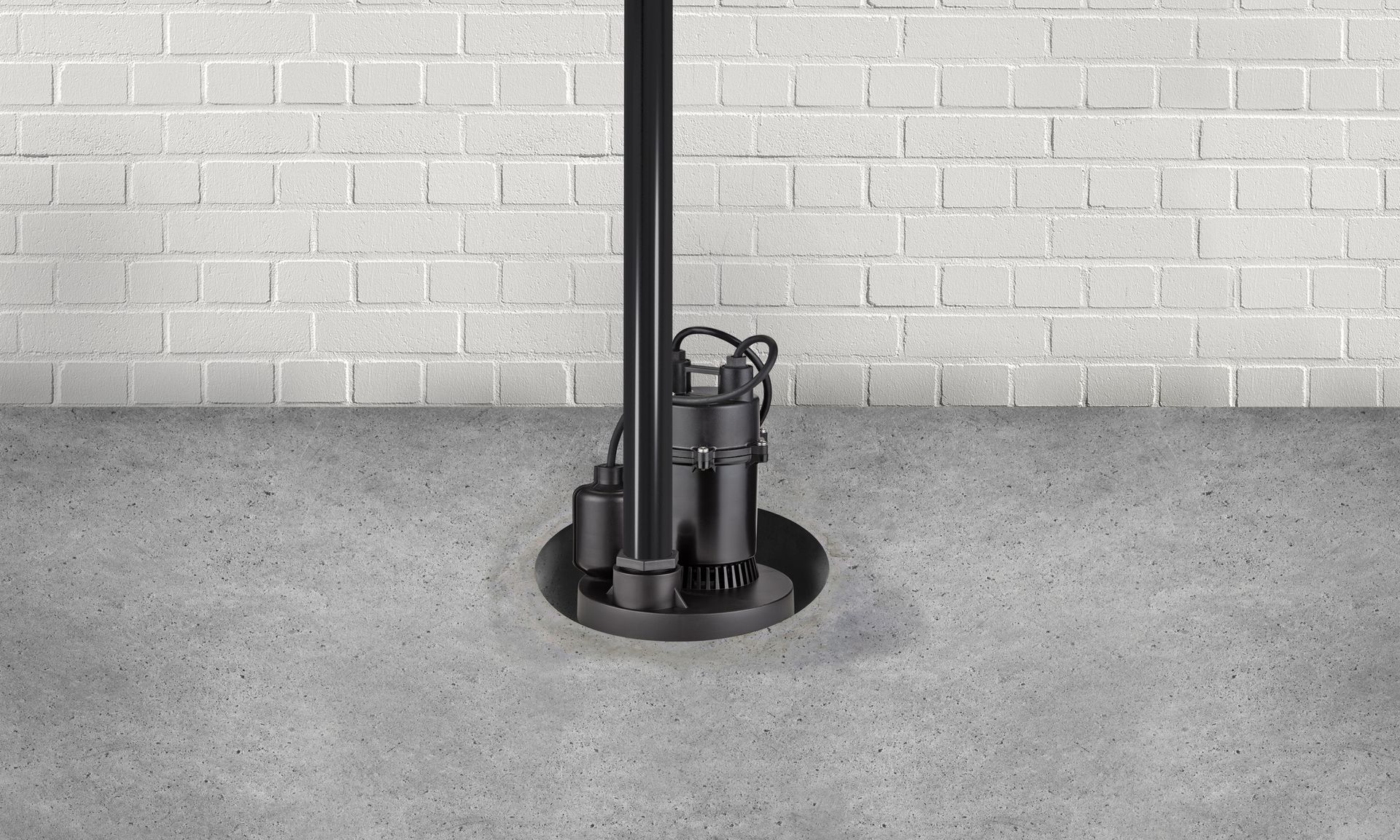 Small black utility pump in a round floor well against a white brick wall