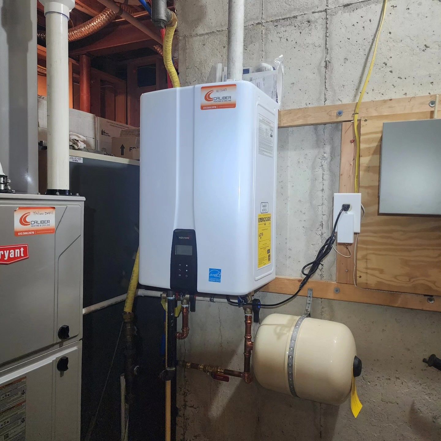 A white water heater is mounted to the wall in a basement.