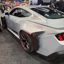 Silver modified sports car at an event; rear view with wide tires and aerodynamic modifications.