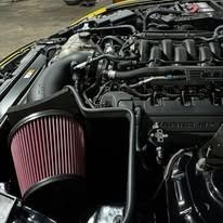 Close-up of a car engine bay, featuring a large red air filter and various engine components.