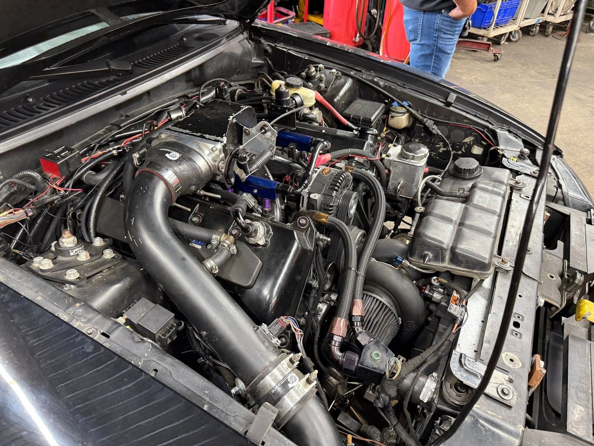 Black car engine bay with modifications, including a large air intake and additional components.