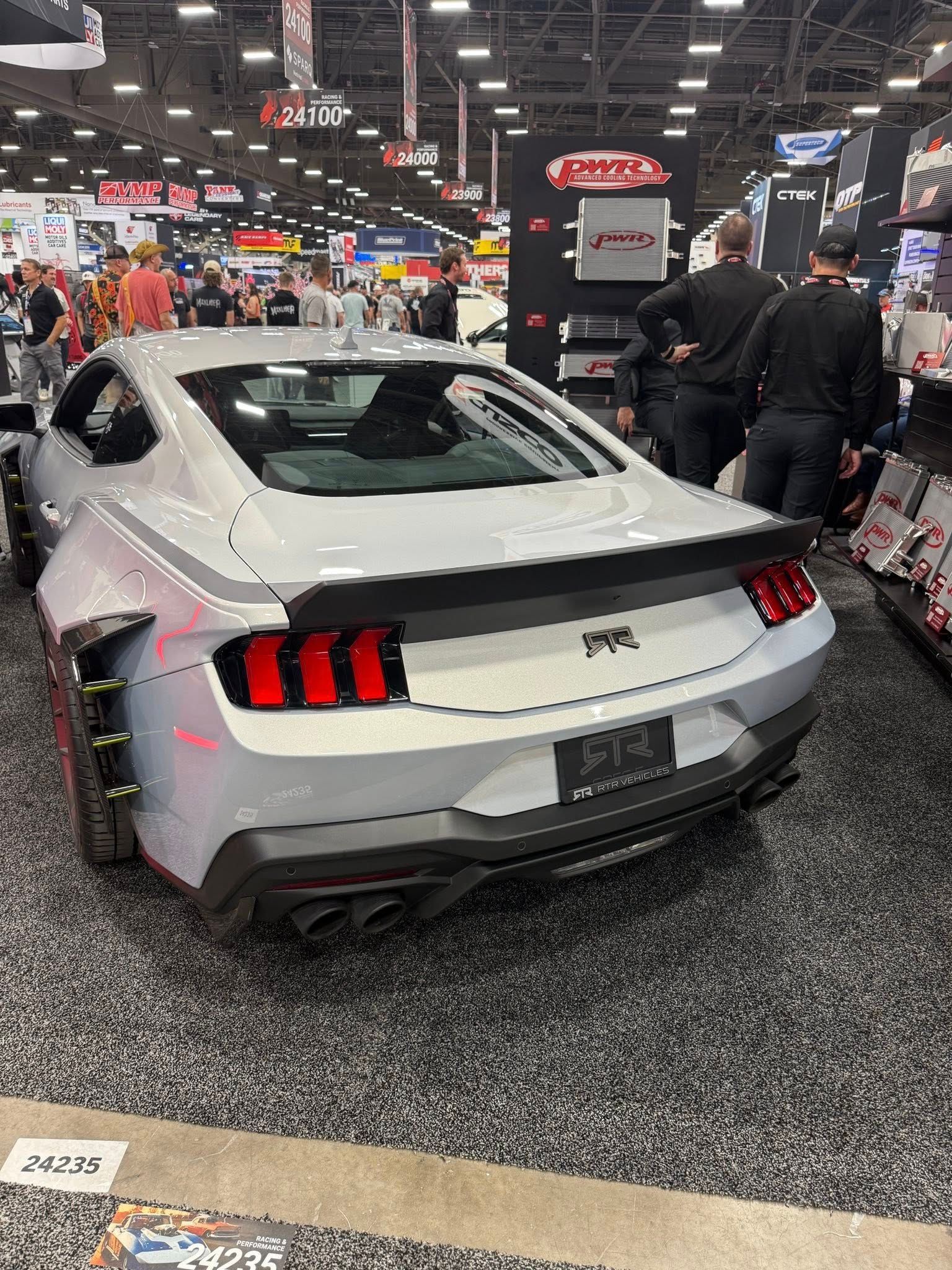 Gray Ford Mustang with widebody kit at a trade show.