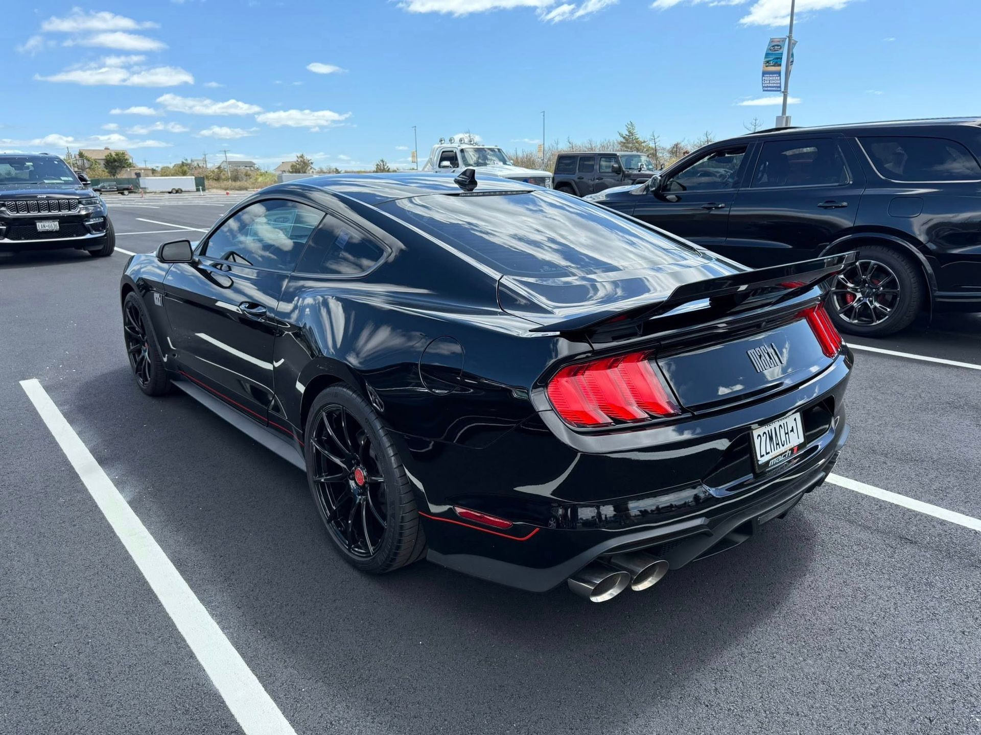 Black Ford Mustang parked in a parking lot on a sunny day.