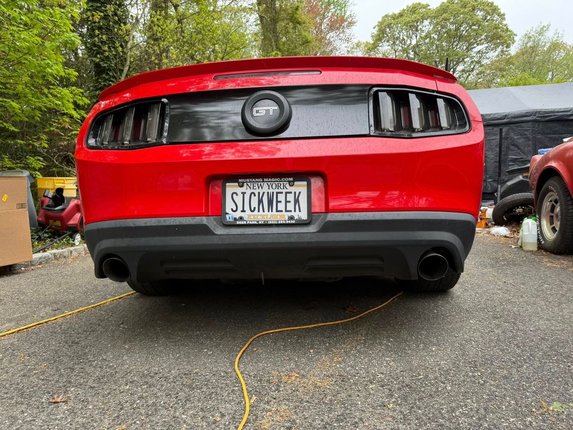 Red Ford Mustang with black accents and license plate that reads 