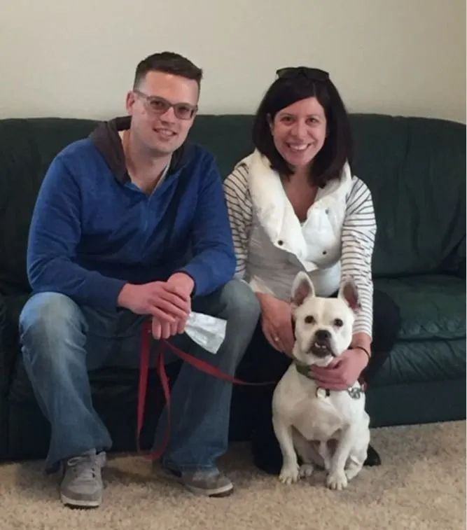 A man and woman sitting on a couch with a dog