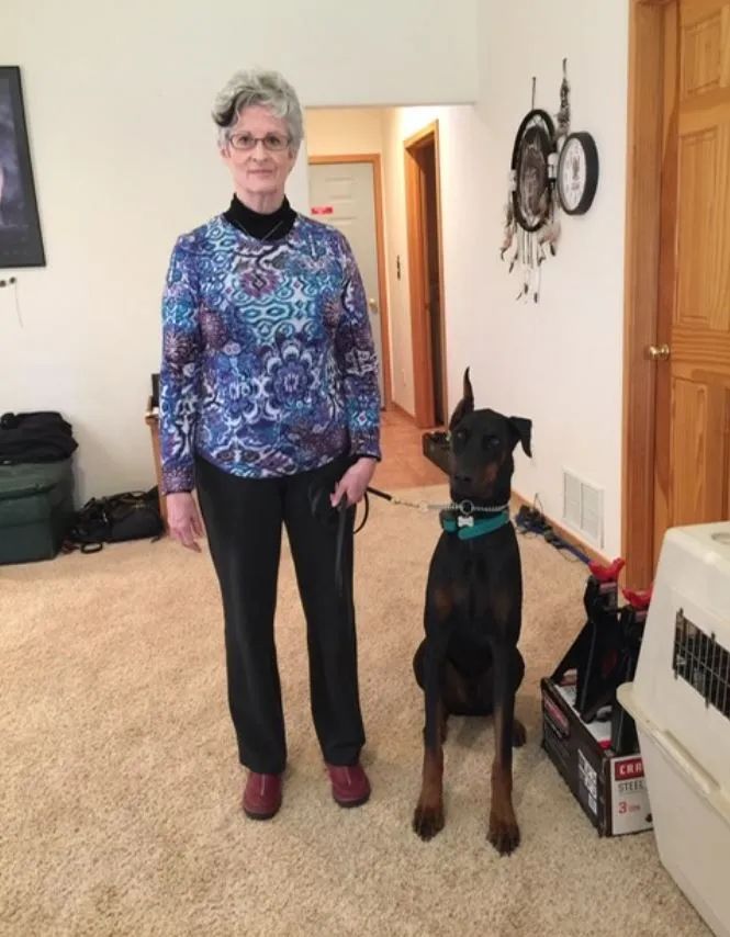 A woman standing next to a dog in a living room