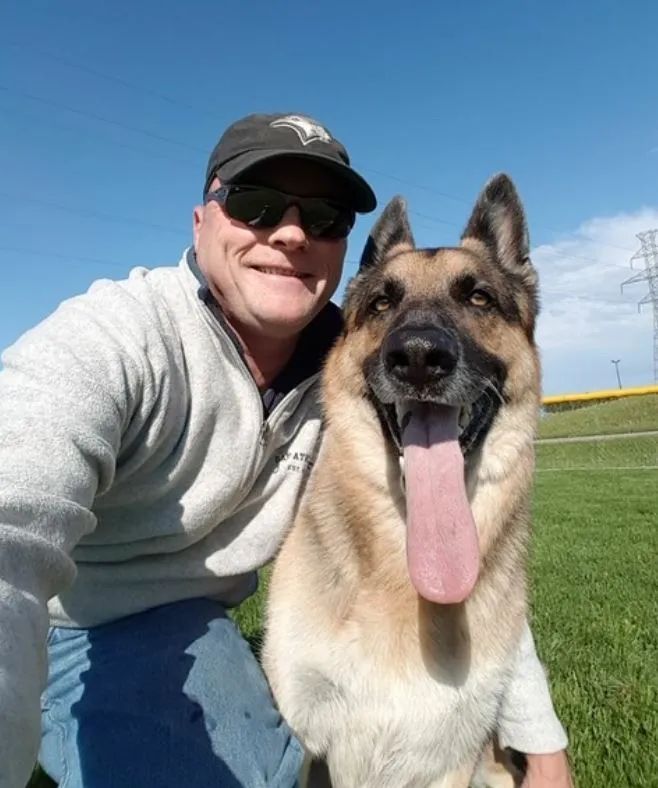 A man and his german shepherd are posing for a picture