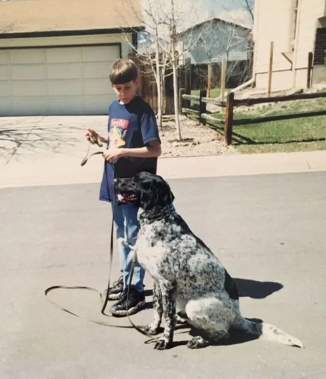 A boy standing next to a dog on a leash