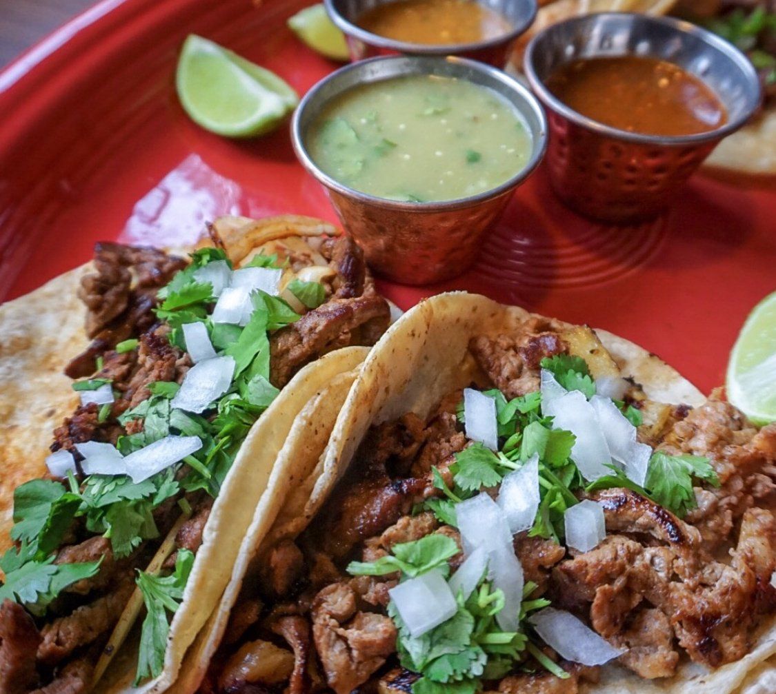 A red plate topped with tacos and sauces