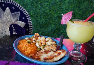 A plate of food and a margarita on a table.