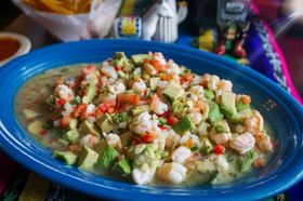 A blue plate topped with shrimp and avocado on a table