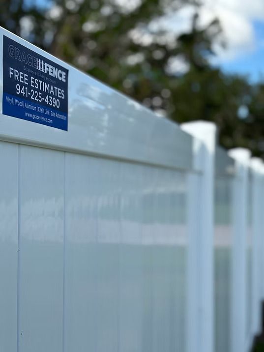 White vinyl fence with blue company sticker offering free estimates.