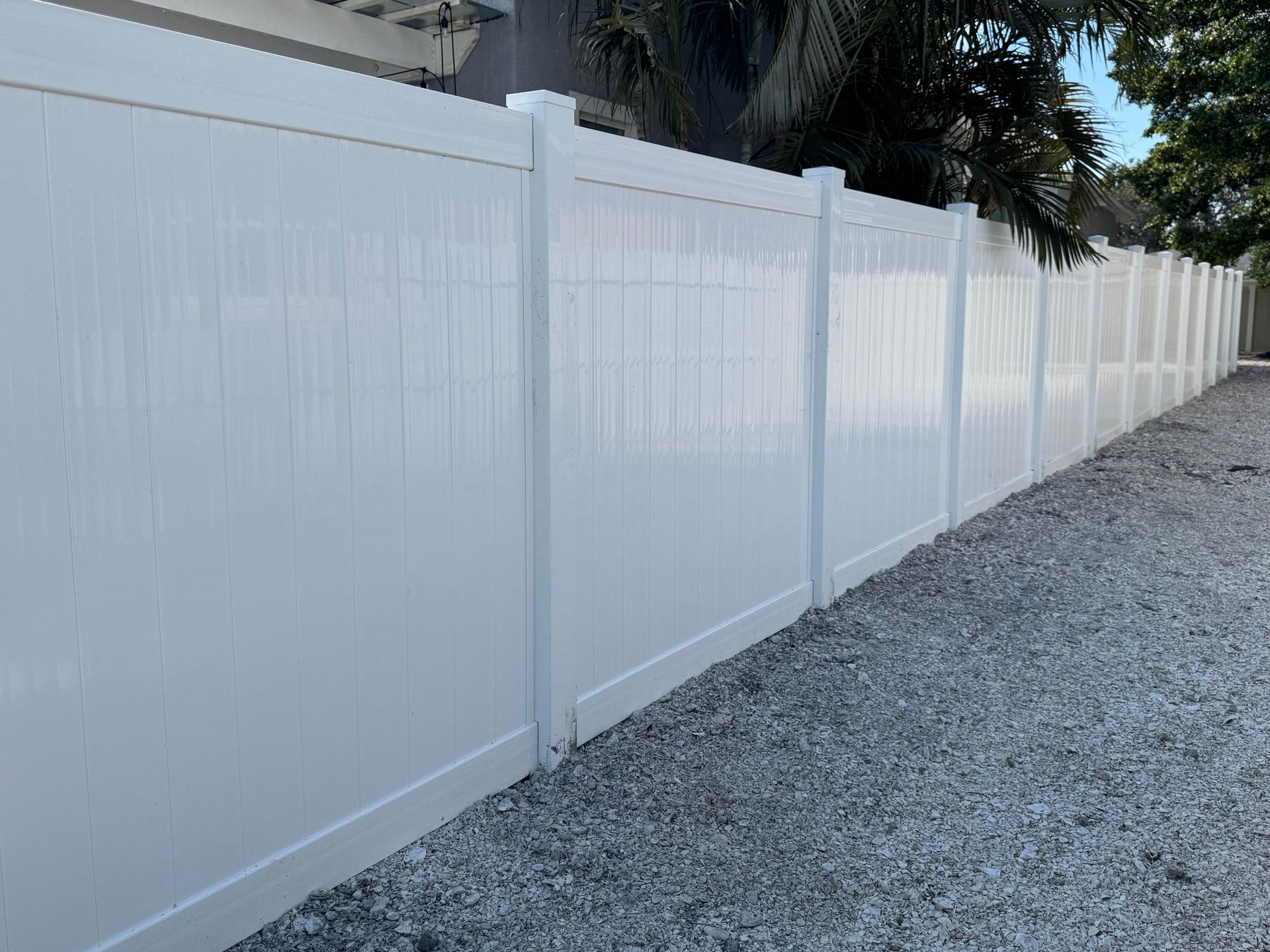 White vinyl privacy fence along a gravel path.