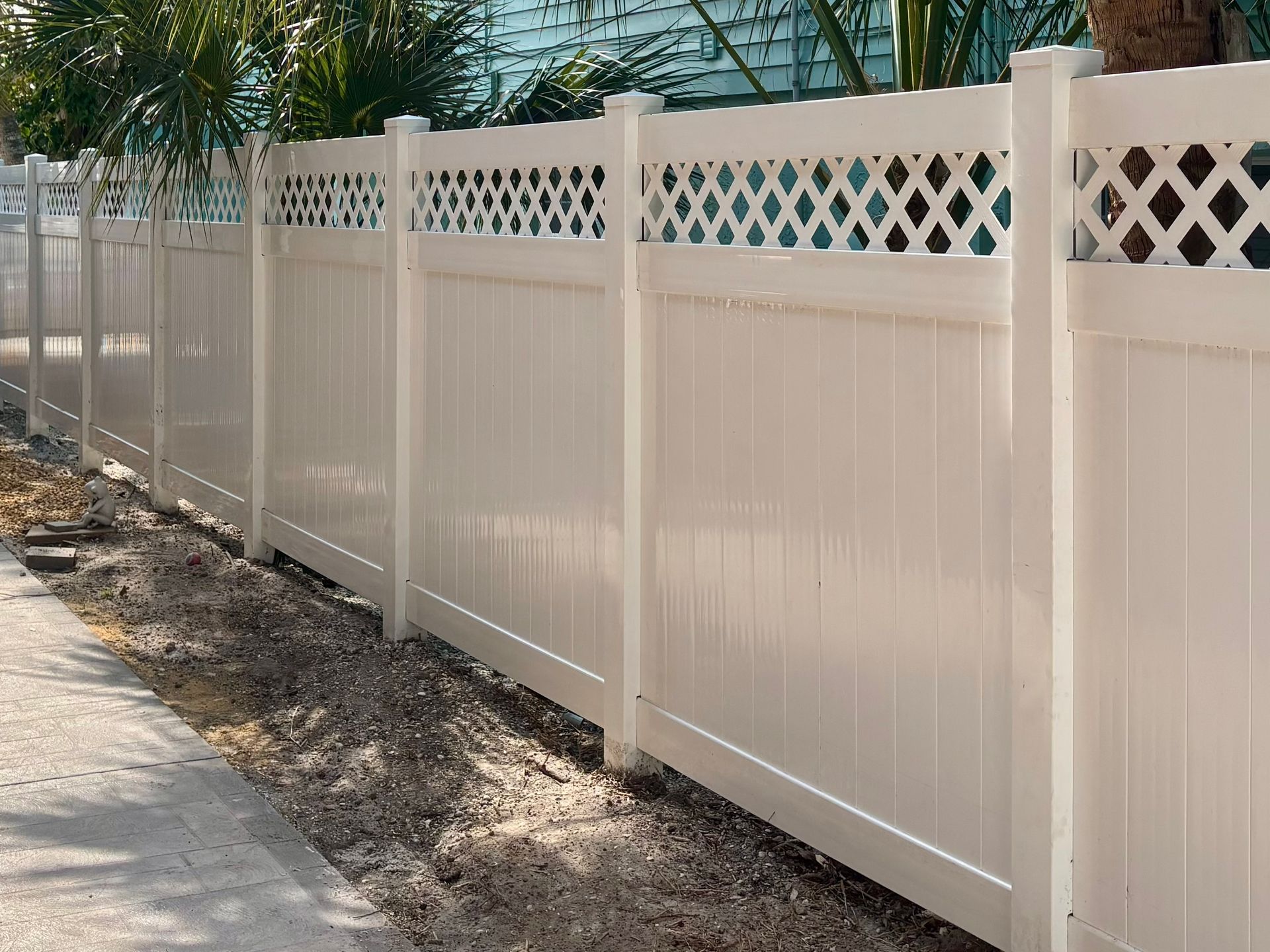 White vinyl fence with lattice top along a sidewalk.