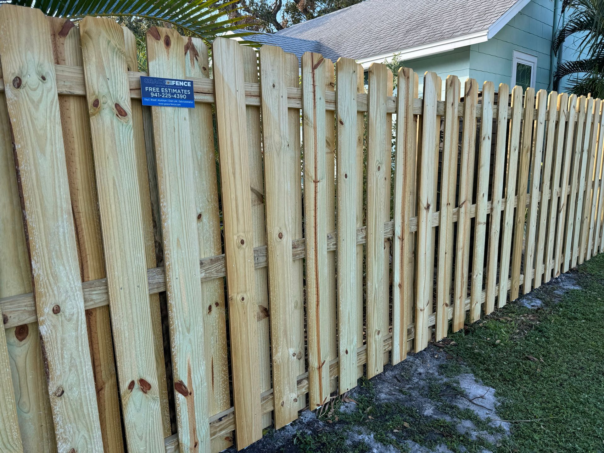 Wooden fence in a yard, with vertical boards and horizontal supports.