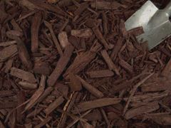 A shovel is sitting on top of a pile of brown mulch.