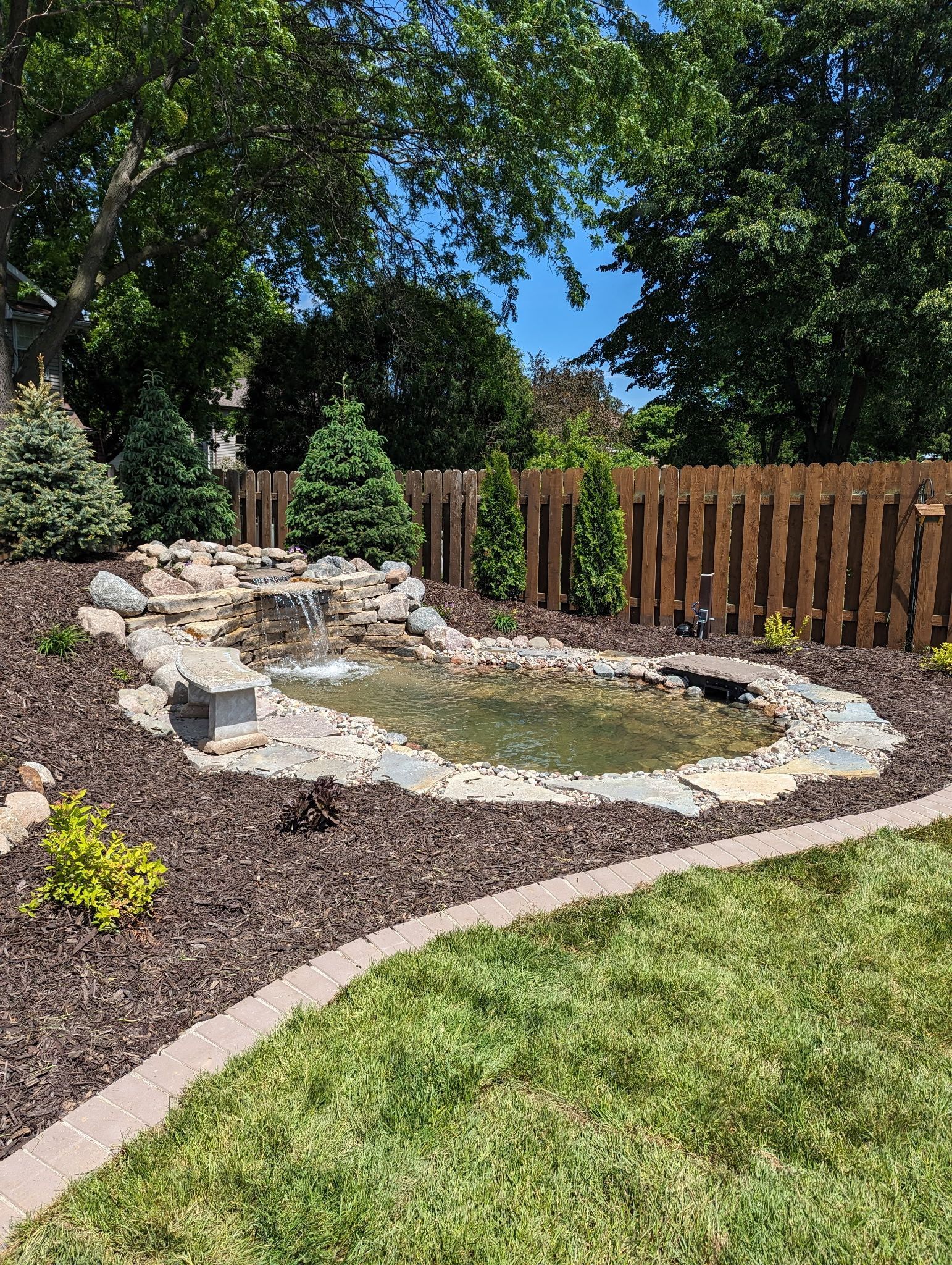 A backyard with a pond and a wooden fence.